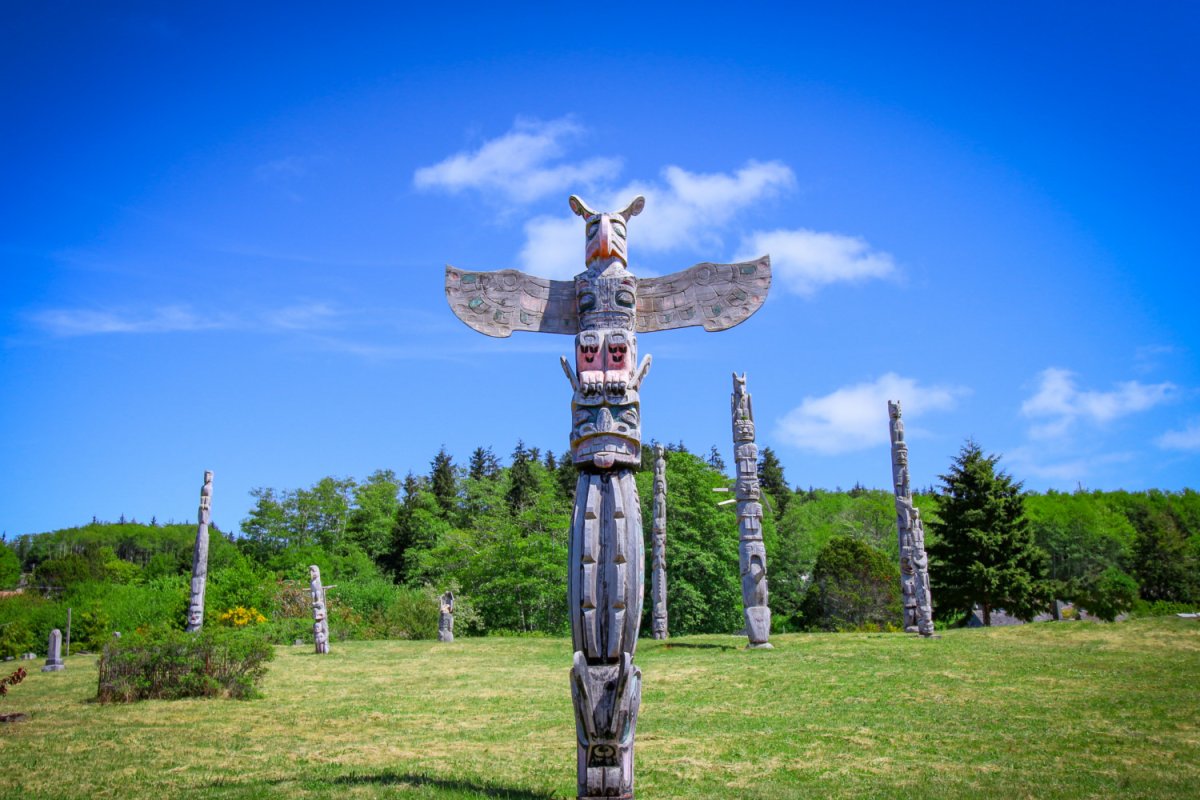 totem poles on green grass in alert bay british columbia