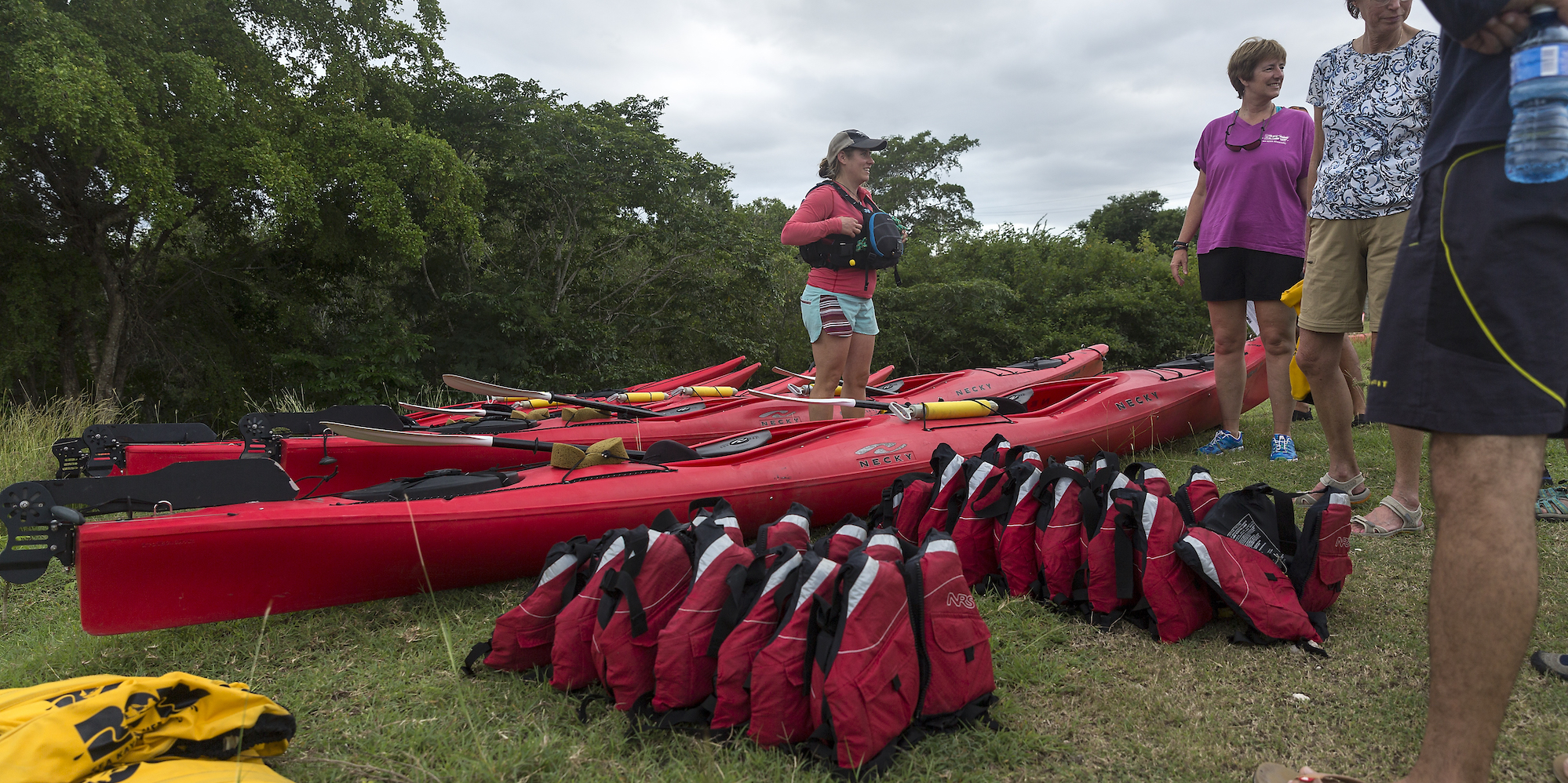 A line of shared PFDs in Cuba beside red sea kayaks ready to be distributed