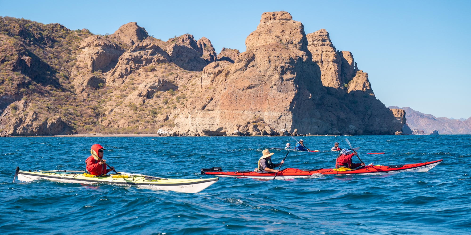 Sea kayakers paddling along the dramatic coastline of Loreto Bay National Park in Baja California Sur